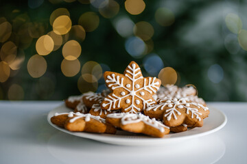 Ginger Christmas cookies on the background of a Christmas tree with lights.