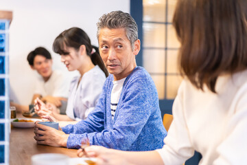 Fototapeta premium レストランのカウンター席でご飯を食べる人々