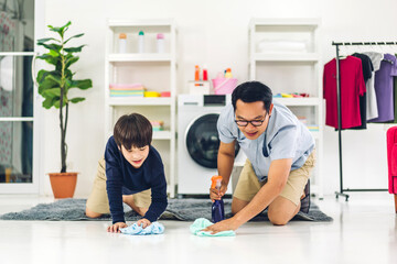 Father teaching asian kid little boy son use disinfectant spray bottle cleaning and washing floor wiping dust with rags while cleaning house together at home