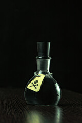 vial of poison with a hazard warning label, on a dark background, toning, short focus