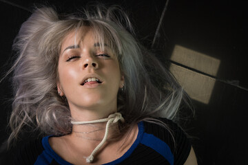 Crime scene simulation: dead girl with hands tied lying on the floor. She was strangled with a...