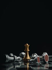 The gold queen chess piece standing with falling silver pawn chess pieces on chessboard on dark...