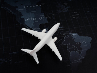 Close-up white plane toy model on world map background, top view, minimal style. Flight, travel,...