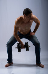 Obraz premium man posing with dumbbells. model in the studio poses, shows muscles, beautiful body relief. spotr, healthy lifestyle