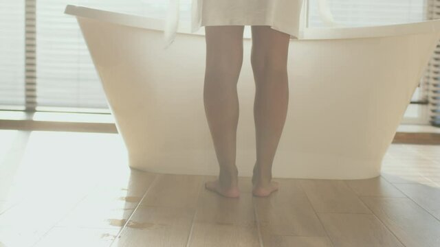 Water spa concept. Unrecognizable african american woman taking off bathrobe and getting into bathtub, tracking shot