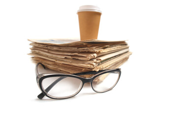 Stack old newspapers, glass of coffee and glasses for reading newspaper news.