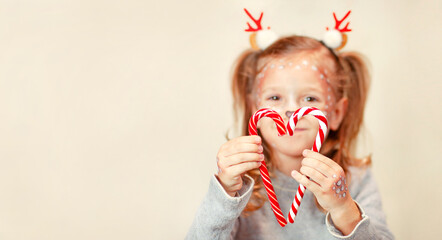 blurry girl in Christmas horns folded lollipops in the shape of a heart