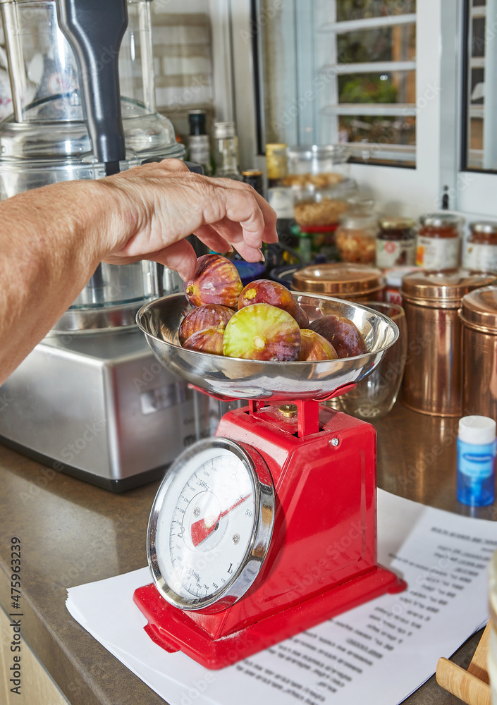 Poster Woman weighs figs on scale in the kitchen to make pie using recipe from the Internet