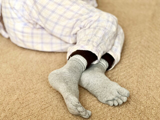 寝巻姿で寝転んだ、靴下を履いた足_足裏から