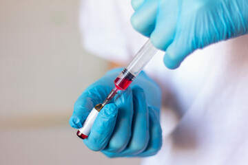 A doctor holding a syringe and an ampoule with medicine .The concept of disease, medical care,...