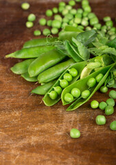 Green peas with leaves on wooden background