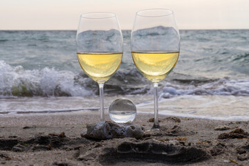 Romantic glass of white wine, on the sea beach. Wine tasting and relaxation at the resort