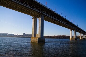 An urban landscape with a bridge over a river. Architecture of urban structures. Bridge construction