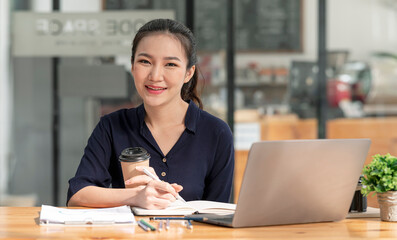 Young asian beautiful and charming busineswoman smiling and working on laptop computer at office.