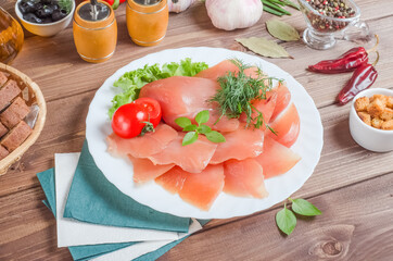 Sliced meat fillet on a white plate on a dark wooden background.