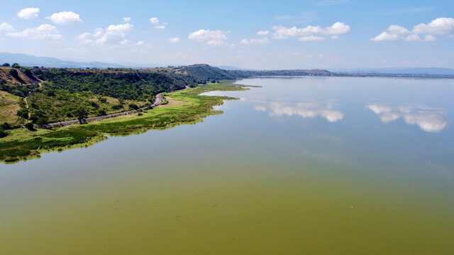Landscape of a lake surrounded by hills under the sunlight and a blue bsky in the countryside