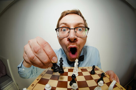 Fisheye portrait of crazy nerd chess player with glasses, looking at camera
