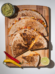 Overhead shot of appetizing quesadillas with guacamole dip, chili and lemon on the side