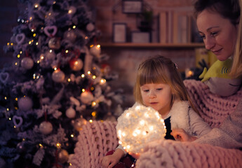 Merry Christmas and Happy Holidays! Mom and daughter decorate the Christmas tree indoors. The morning before Xmas. Portrait loving family close up. - 475972412