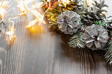 Christmas composition on a wooden background, Christmas cones and balls, green sprigs of needles, yellow lanterns in the form of stars and space for text, beautiful decoration for the home and design