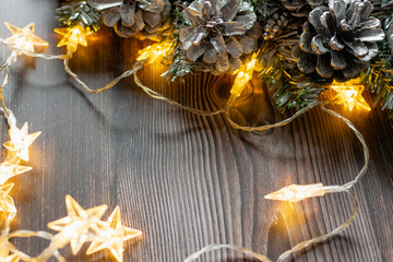 Christmas composition on a wooden background, Christmas cones and balls, green sprigs of needles, yellow lanterns in the form of stars and space for text, beautiful decoration for the home and design