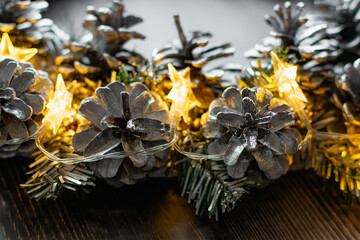 Christmas composition on a wooden background, Christmas cones and balls, green sprigs of needles, yellow lanterns in the form of stars and space for text, beautiful decoration for the home and design