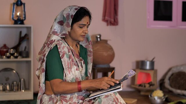 A modern middle-aged housewife calculating her monthly income - Village home  salary  savings. A rural housewife with five hundred rupees banknotes - daily income  banking  and finance  an independ...