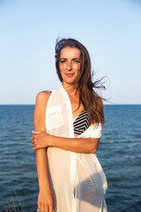 Fototapeta na wymiar Beautiful young woman in a light pareo on the beach.