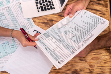 Naklejka premium two employees at work fill out tax forms 1040 at the office desk.