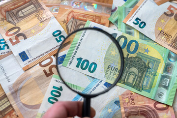 magnifying glass lie on pile of euro money
