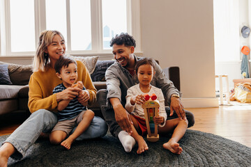 Two young parents playing with their son and daughter at home