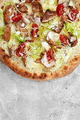 Delicious pizza Caesar style with white sauce, chicken, parmesan, egg, cherry tomatoes and fresh lettuce at wooden background. Restaurant pizzeria menu with delicious taste pizza Caesar.