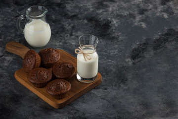 Milk with cookies on cutting board dark backround