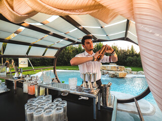 Young Caucasian barman making a refreshing cocktail outdoors at an event