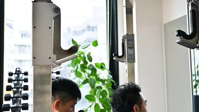 バーベルの筋トレを教えるトレーナーとプライベートレッスンを受ける人	