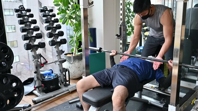 筋トレを教えるトレーナーとプライベートレッスンを受ける人　広角