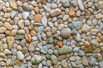 Rounded pebbles held by concrete in a wall suitable for background
