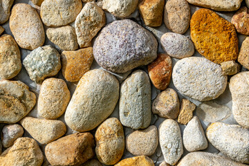 Rounded pebbles held by concrete in a wall suitable for background
