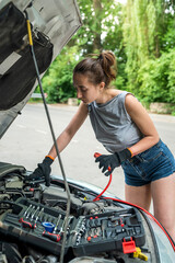 woman holding  jumper cable for recharge the battery car for repairing broken car