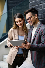 Successful young business people talking, working together in front of modern business building