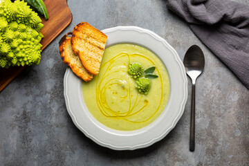 Creamy romanesco broccoli soup with olive oil and toast bread. Vegan food. Fresh raw roman broccoli...