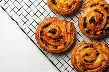 Just baked pain aux raisins on cooking wire rack. Buns are also called escargot or pain russe, is a...