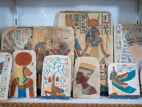 Colored stone tablets in a gift shop featuring Egyptian-themed drawings of ancient gods. Luxor, Egypt.
