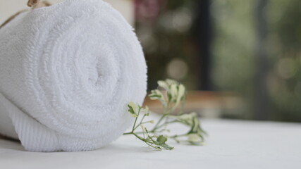 Rolls of white towels placed on a wooden table including spa sets