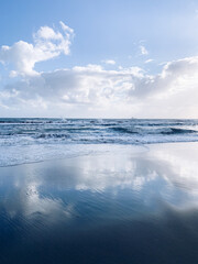Seascape, white clouds on the blue sky reflection, sea surface, sand beach