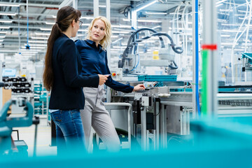 Businesswoman discussing with colleague at factory production line
