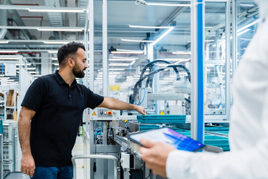 Businessman explaining maintenance engineer over factory production line