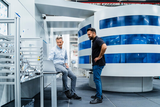 Businessman discussing over laptop with engineer in industry