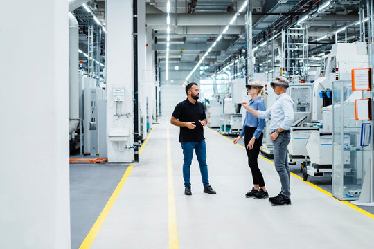 Engineer discussing with businessman and businesswoman using augmented reality glasses in industry