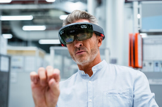 Businessman using augmented reality eyeglasses at factory